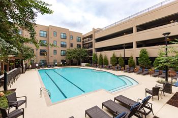 A large swimming pool surrounded by lounge chairs and trees.